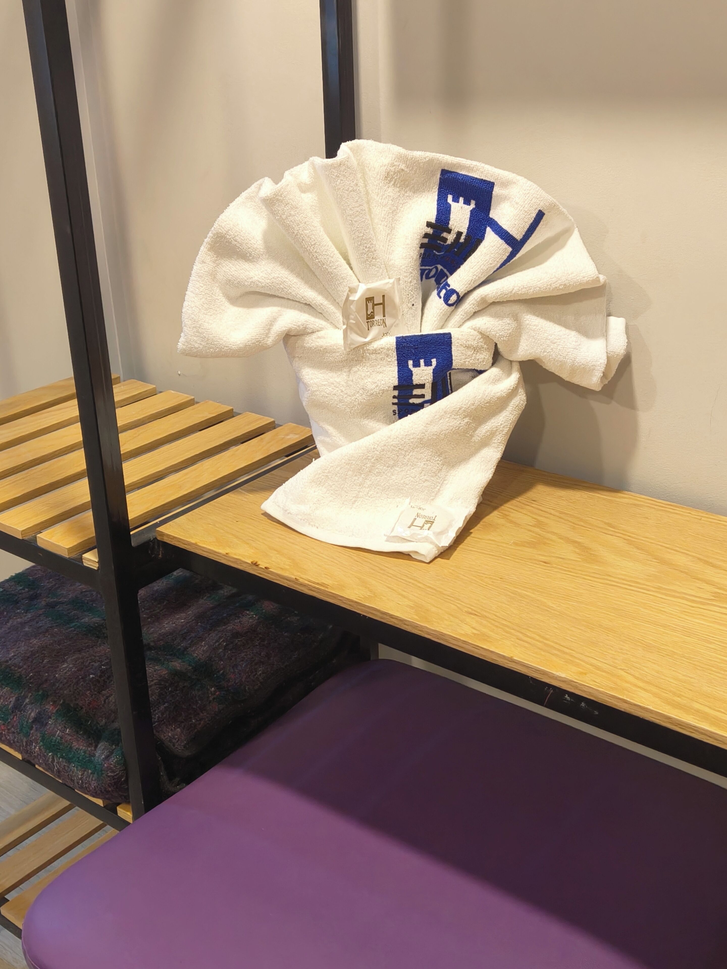 Una cama litera con una manta blanca y una toalla azul.