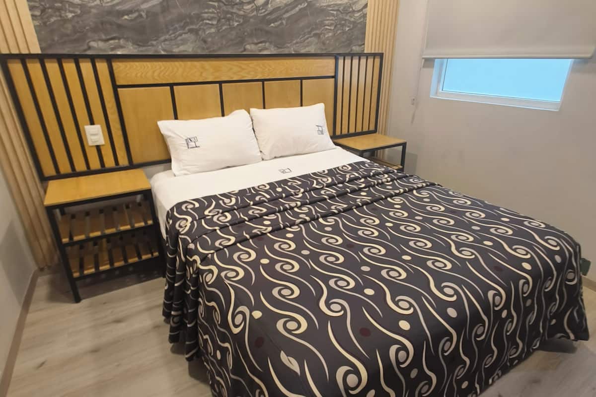 Un dormitorio con cama, mesita de noche, ventana con persianas y pared con diseño de mármol.