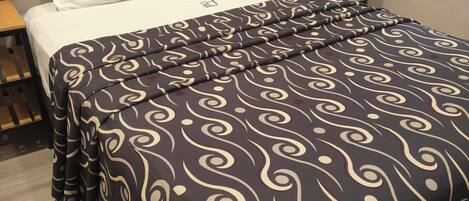Una cama bien hecha con una colcha estampada, un cabecero de madera y una mesita de noche.