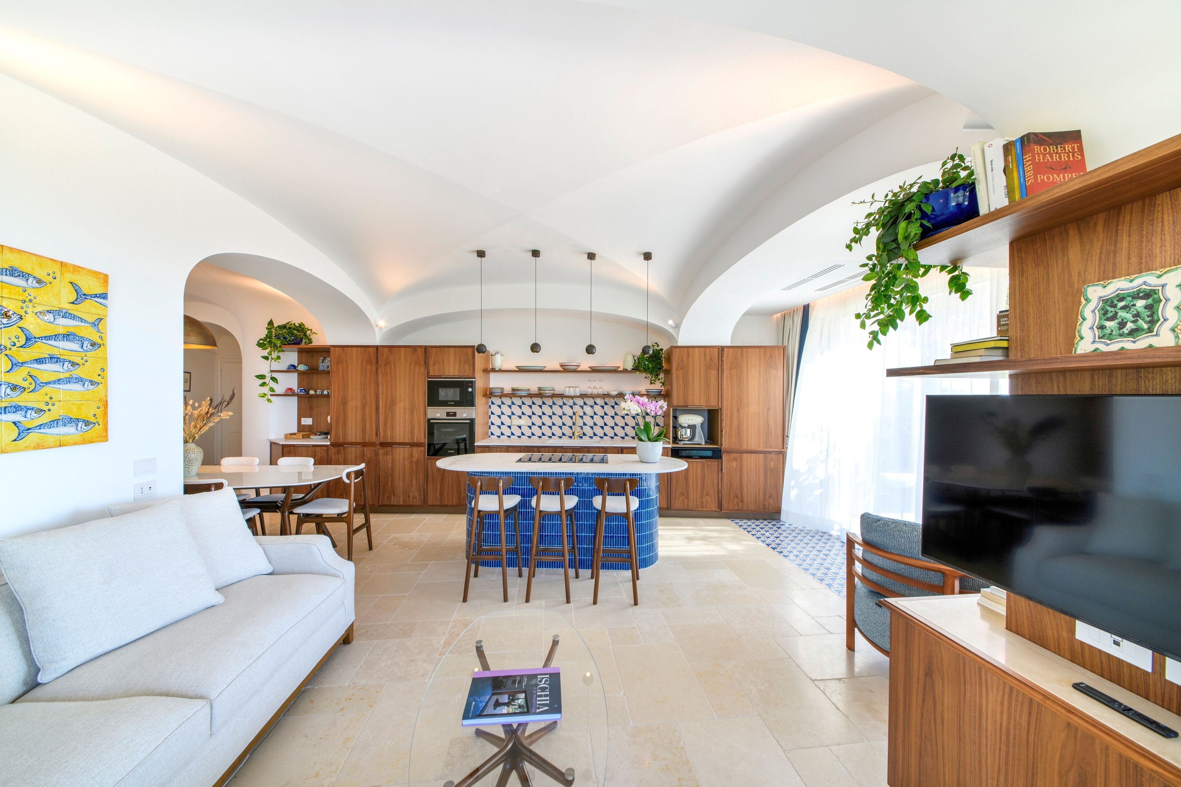 A modern kitchen with a central island, wooden cabinets, and a dining area with a sofa and chairs.