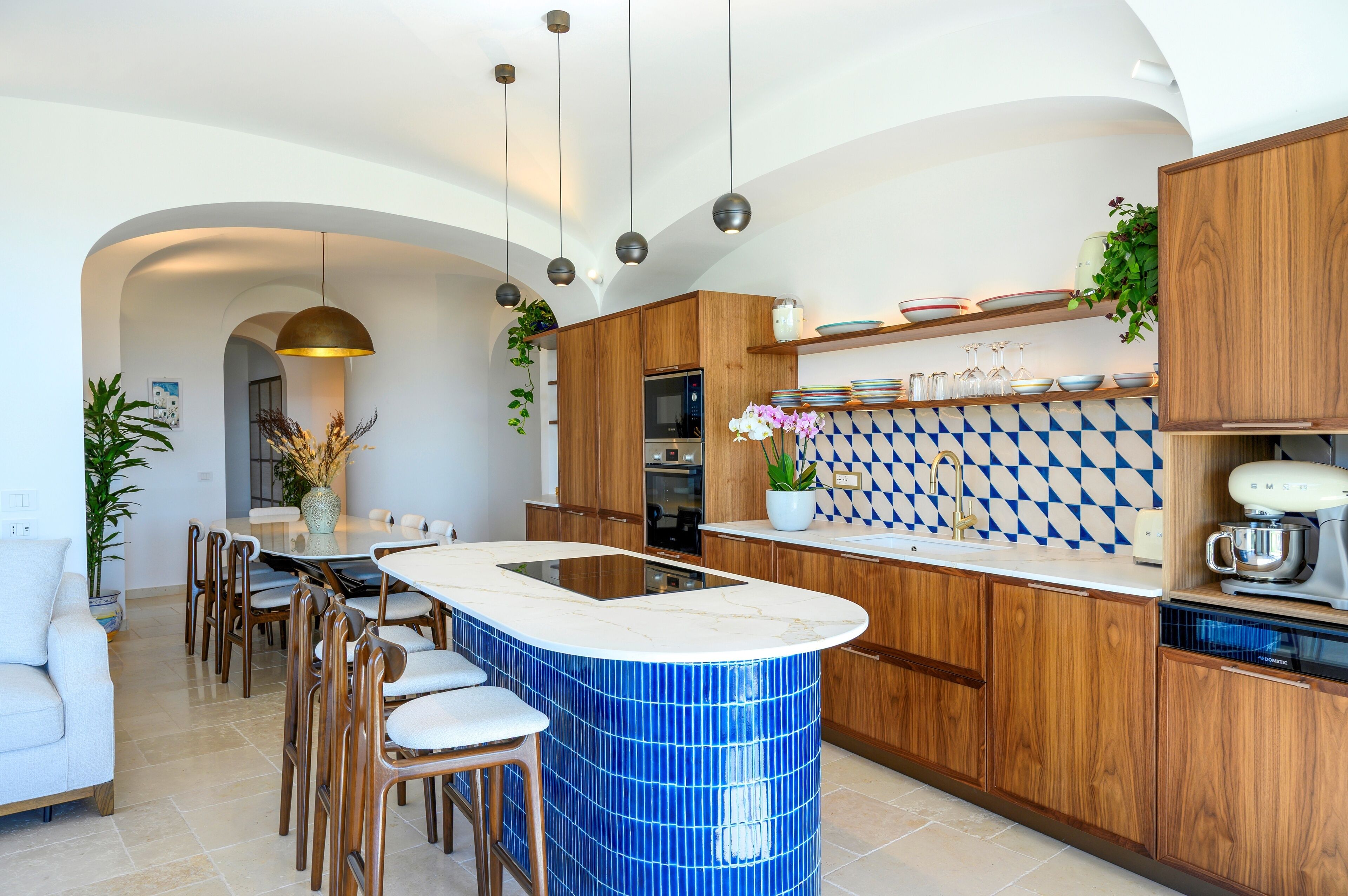 A modern kitchen with a central island, wooden cabinets, and a blue-tiled backsplash.