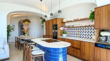 A modern kitchen with a central island, wooden cabinets, and a blue-tiled backsplash.