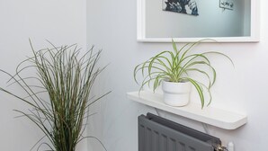 Et hjørne med en radiator, en stueplante og et billede i ramme på væggen.