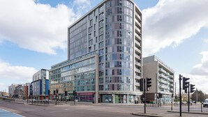 En bygning med flere etager, en buet facade, store vinduer og butikslokaler i stueplan.