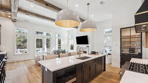 Una cucina moderna con un'isola grande, illuminazione a sospensione e vista all'esterno.