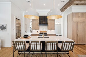 A modern kitchen with a central island, pendant lighting, and wooden cabinetry. - Anna Blue| Watercolor | Private Pool | Bikes (Watercolor)
