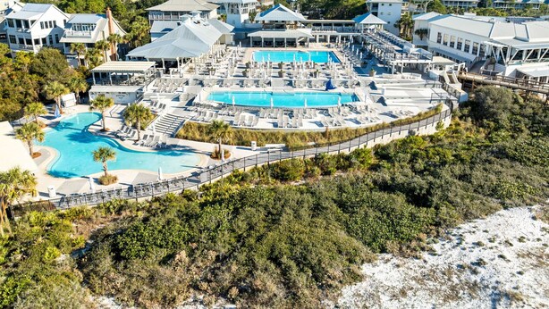 Un resort con diverse piscine, una spiaggia e vista sul quartiere circostante.
