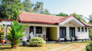 A white building with a red roof, surrounded by greenery and palm trees. - Zeylon Villa Talalla (Talalla)