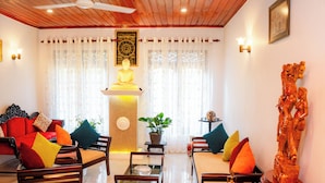 A well-lit living room with a sofa, chairs, a coffee table, and a Buddha statue. - Zeylon Villa Talalla (Talalla)