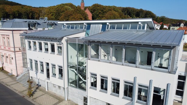 Un edificio moderno con varios pisos, ventanas amplias y una escalera que lleva a los niveles superiores.