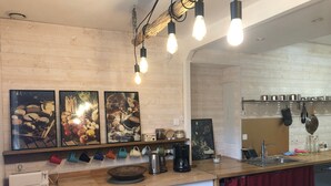 A kitchen with wooden cabinets, a wooden countertop, hanging light bulbs, and various kitchen items. - Gîte Bonaty – Comfortable, Quiet, Cozy Furnished Home for 2 to 9 Guests (Soulgé-sur-Ouette)