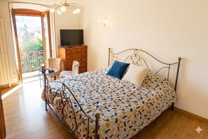 Ein Schlafzimmer mit einem Bett, einem Fernseher, einem Schminktisch und einem Sessel.