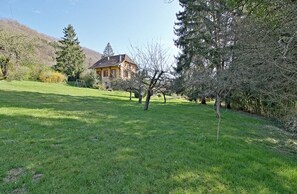 A house surrounded by a grassy area with trees and a mountain in the background.