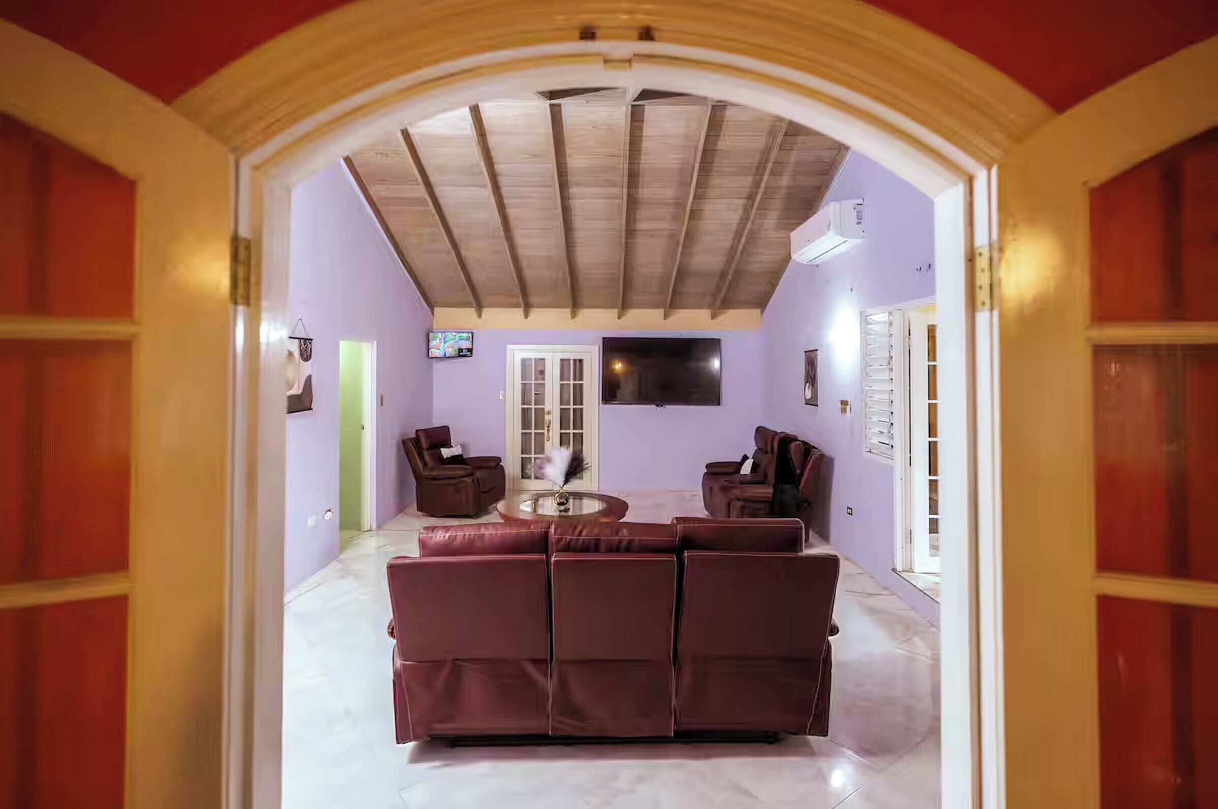 A living room with a sectional sofa, a coffee table, and a flat-screen TV mounted on the wall.