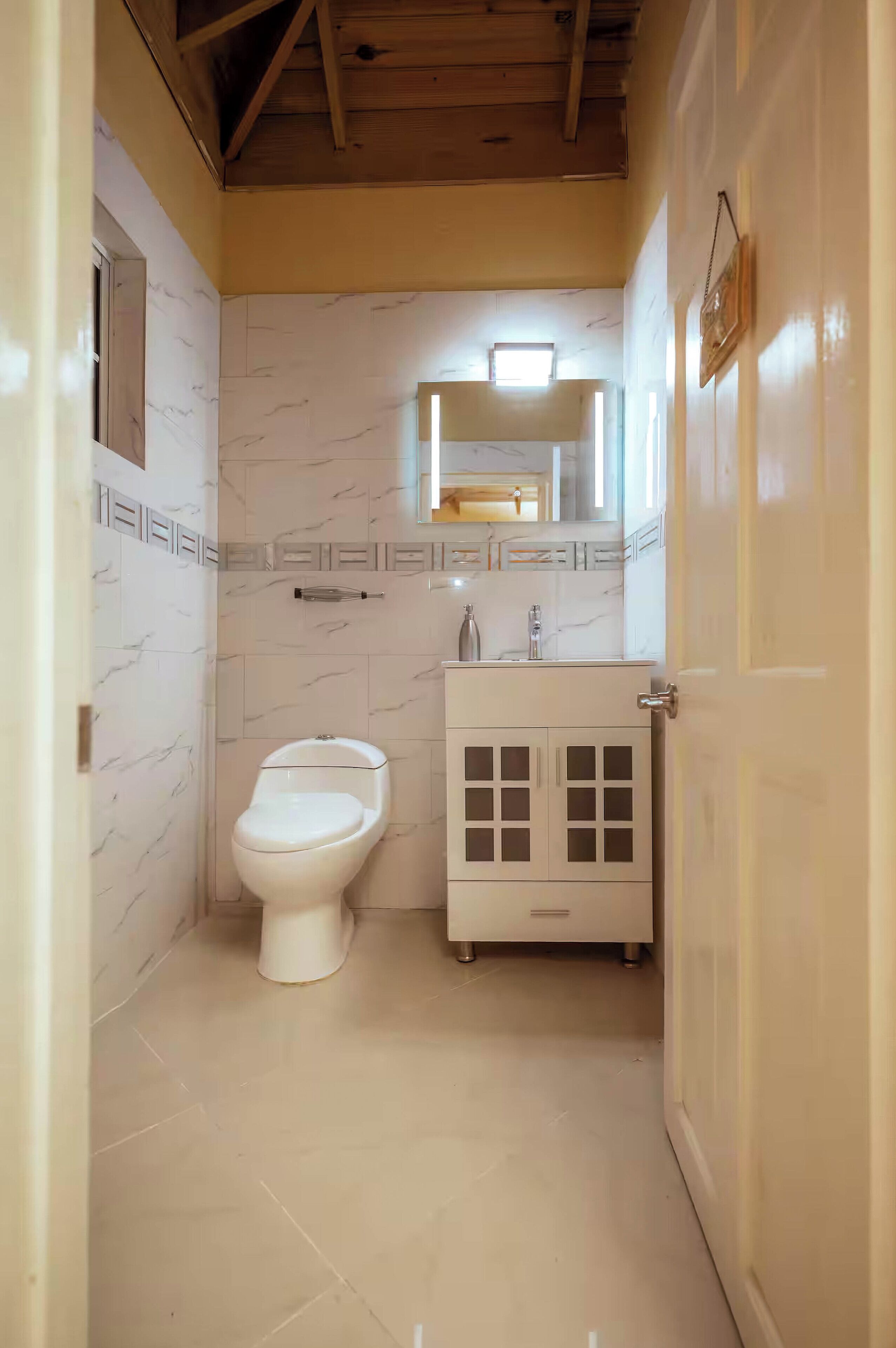 A small bathroom with a toilet, sink, and cabinet.