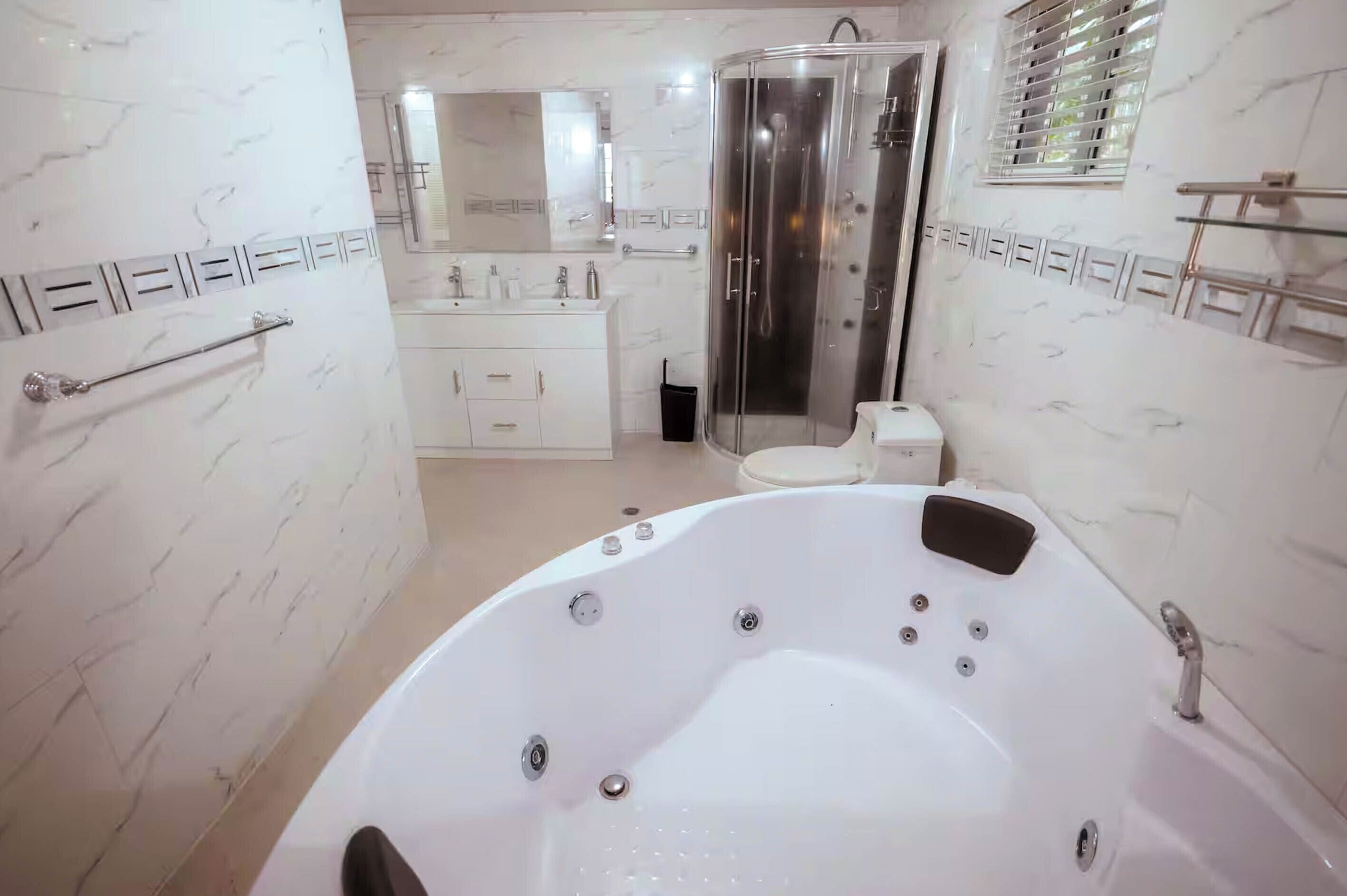 A modern bathroom with a large jacuzzi tub, a glass-enclosed shower, and a vanity with a mirror.
