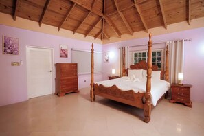 Une chambre à coucher avec un lit à baldaquin en bois, une commode, une table de chevet et une fenêtre avec des rideaux.
