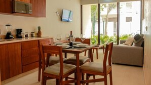 Una cocina moderna con armarios de madera, un microondas y un comedor con cuatro sillas de madera y una mesa dispuesta para cuatro personas.