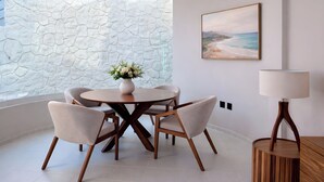 A dining area with a round table, four chairs, a vase with flowers, a painting on the wall, and a lamp. - Duplex w/pool+Bay & Sunset Views by Zona Romantica (Puerto Vallarta)