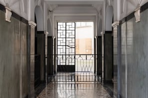 Ein Korridor mit einem geometrischen Metallgitter, Marmorwänden und einem spiegelnden Boden.