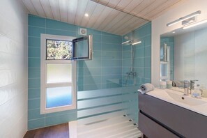 Ein Badezimmer mit Dusche, einem Fenster und einem Waschbecken mit Toilettenartikeln.