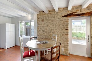 Eine Steinsäule, eine weiße Tür, ein weißer Tisch mit Stühlen und ein weißer Kühlschrank.