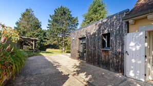 A modern building with a gravel driveway, wooden exterior, and a white door. - Charming 3-Star House with Heated Saltwater Pool and Private Garden (Sarlat-la-Canéda)