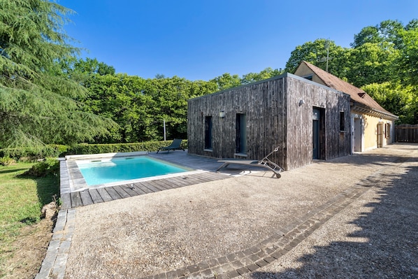 Ein Holzhaus mit Pool und Terrassenbereich.