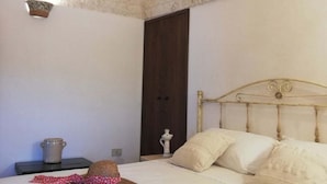 Een slaapkamer met een stenen plafond, een houten bed en een nachtkastje met een lamp.