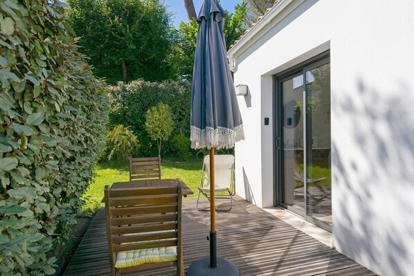 Une terrasse en bois avec un banc, une table et un parasol bleu.