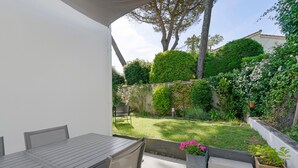 A patio with a table and chairs, a grassy yard, and a white building in the background. - Cozy Room with Terrace and Pool – Breakfast Included (Saint-Palais-sur-Mer)
