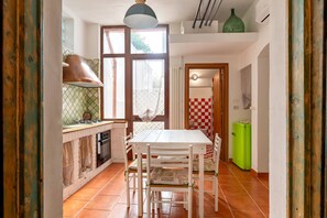 Eine Küche mit Esstisch, Stühlen, einem grünen Kühlschrank und einem Fenster mit Vorhängen.