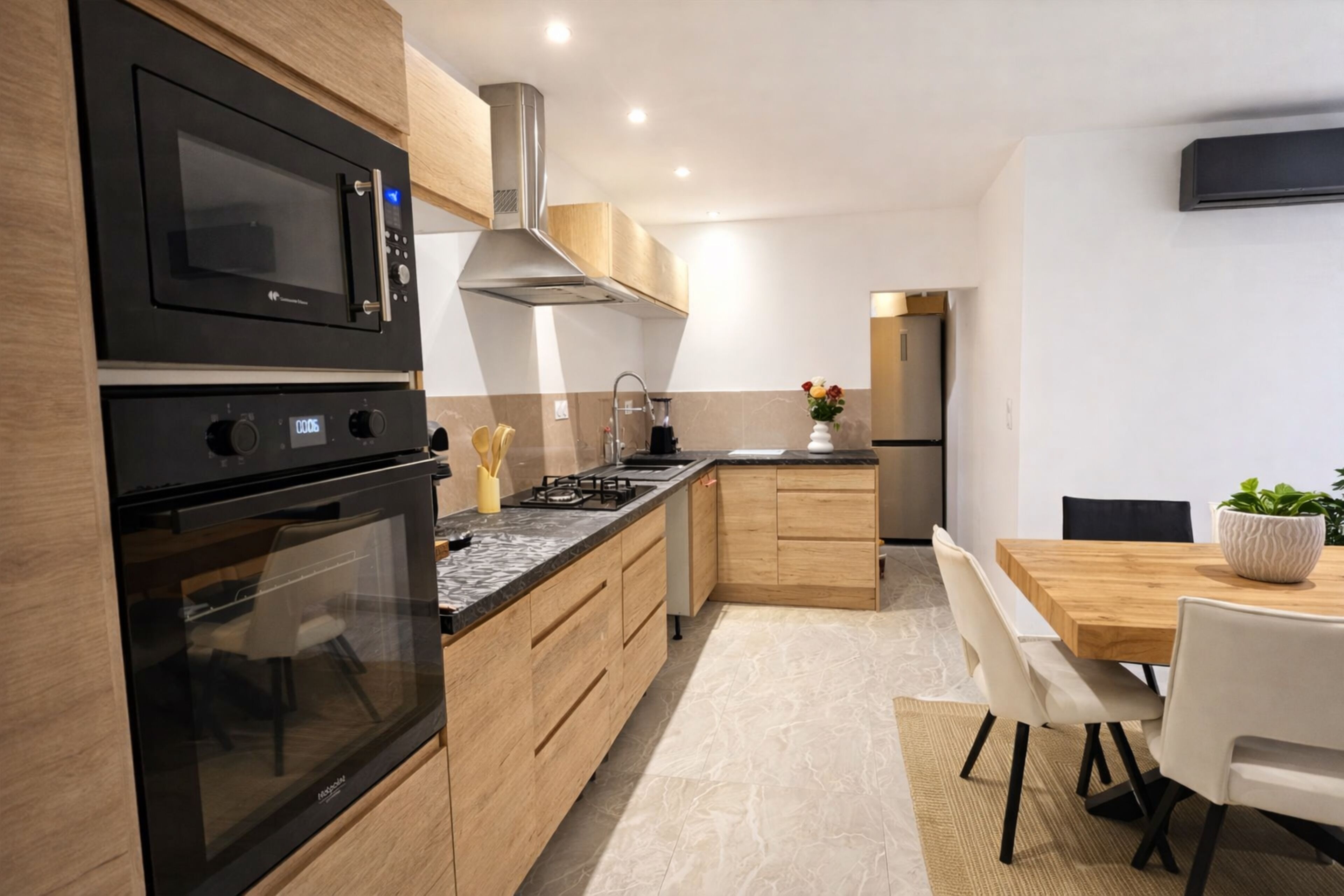 Eine moderne Küche mit integrierten Geräten, Holzschränken und einem Essbereich mit Tisch und Stühlen.