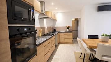 Eine moderne Küche mit integrierten Geräten, Holzschränken und einem Essbereich mit Tisch und Stühlen.