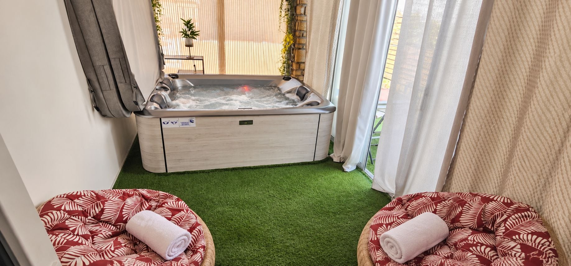 Et spa-rum med jacuzzi, to komfortable siddepladser og en gulvbelægning af grøn kunstgræs.