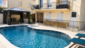 Une piscine dotée d’un espace couvert, de mobilier d’extérieur et d’un mur en pierre.