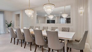 A dining room with a large rectangular table, six upholstered chairs, and three crystal chandeliers. - 8BR Villa w/ Pool & Game Room Windsor Cay (Clermont)