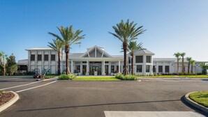 A modern building with a symmetrical facade, large windows, and palm trees in the foreground. - 8BR Villa w/ Pool & Game Room Windsor Cay (Clermont)