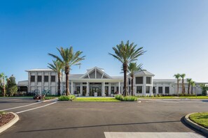 A modern building with a symmetrical facade, large windows, and palm trees in the foreground. - 8BR Villa w/ Pool & Game Room Windsor Cay (Clermont)