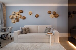 A living room with a sofa, patterned pillows, a coffee table, and a wall decorated with hats.