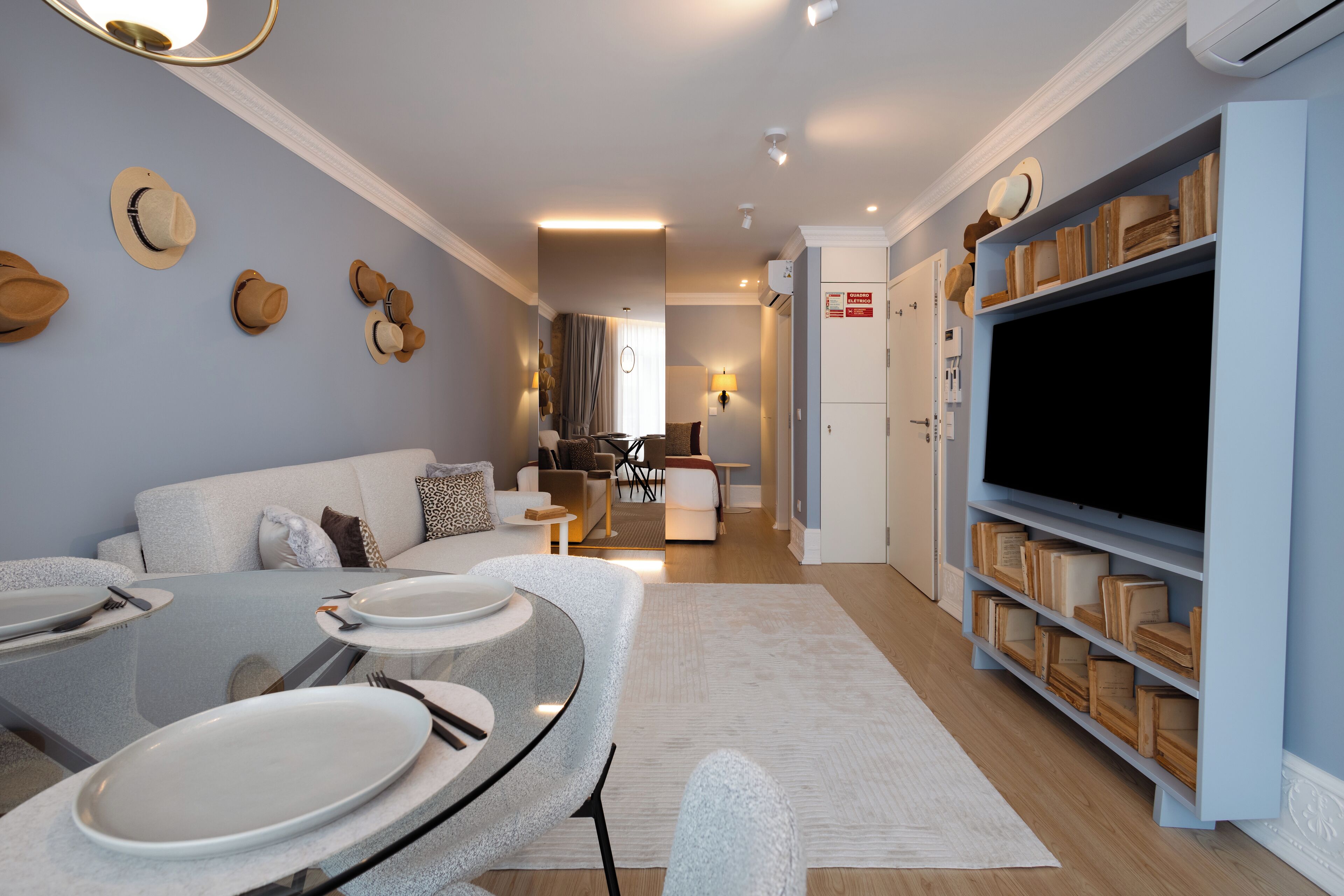 A modern living room with a dining area, a flat-screen TV, and a bookshelf.