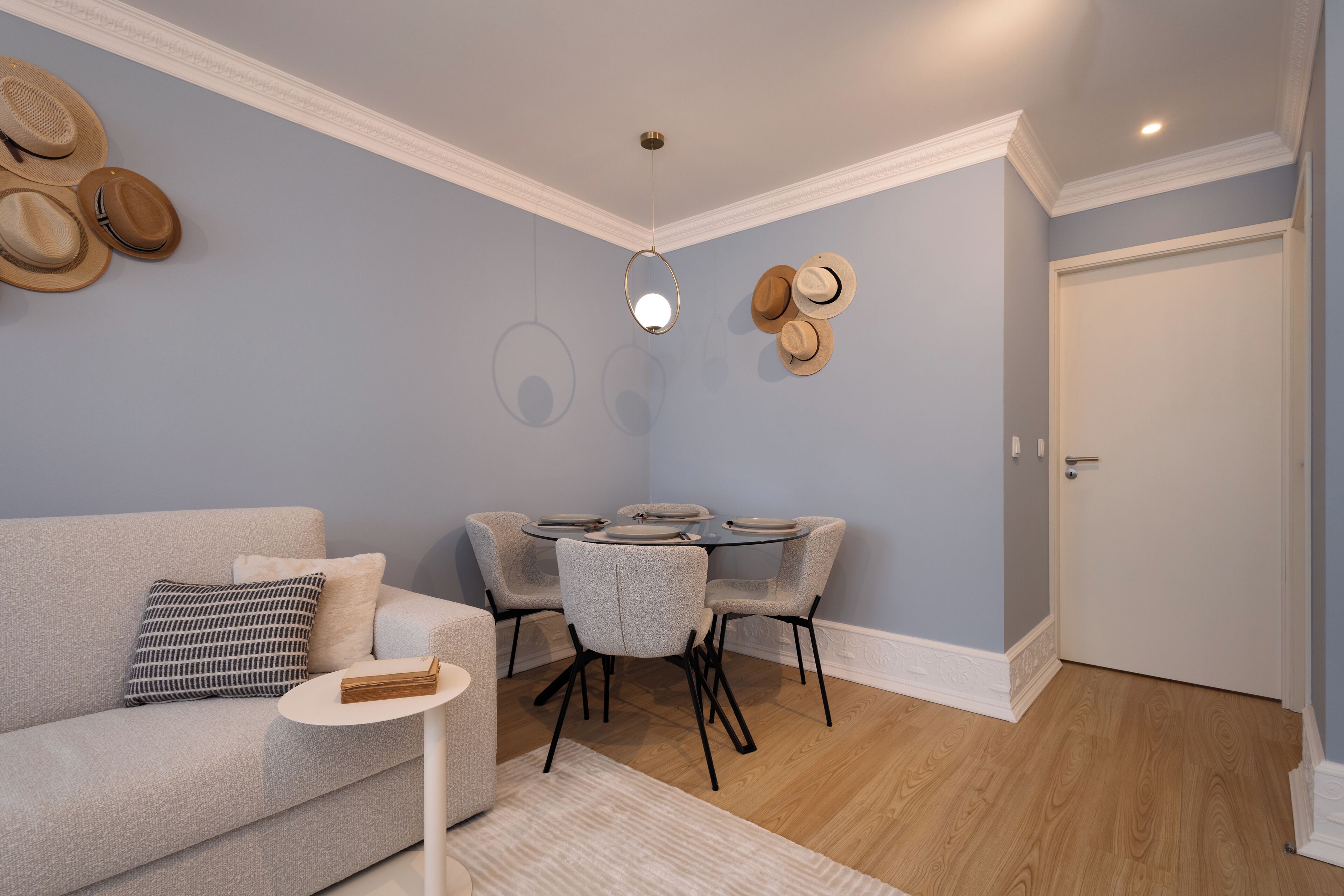 Una sala de estar con sofá, mesa de centro, mesa de comedor y sillas, y una puerta.
