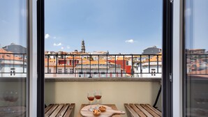 A balcony with a table, two glasses of wine, and a pastry.