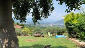 Ein Garten mit Baum, zwei Stühlen, Grill und Schwimmbecken.