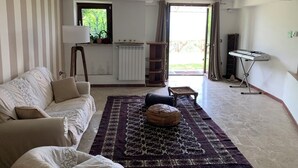 Ein Wohnzimmer mit einer Couch, einem Teppich mit Muster, einer Heizung, einem Fenster und einem Klavier.