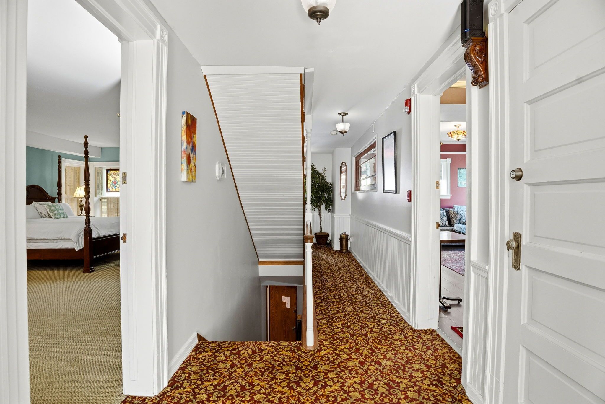 A hallway with a patterned carpet, white walls, and a door leading to a bedroom.