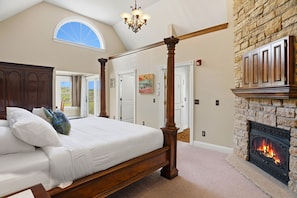 A bedroom with a four-poster bed, a fireplace, and a large window. - St. Croix Valley Inn (Shafer)