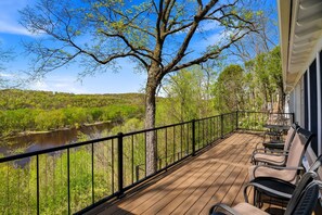 A wooden deck with outdoor furniture, a river view, and a tree. - St. Croix Valley Inn (Shafer)