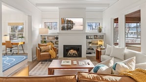 A living room with a fireplace, a sofa, a coffee table, and a desk with a chair.