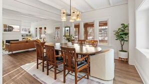 A dining area with a round table, wooden chairs, and a chandelier.